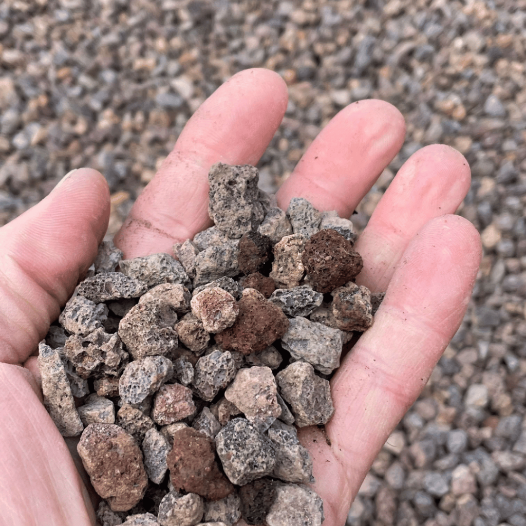 A hand holding scoria crushed rock