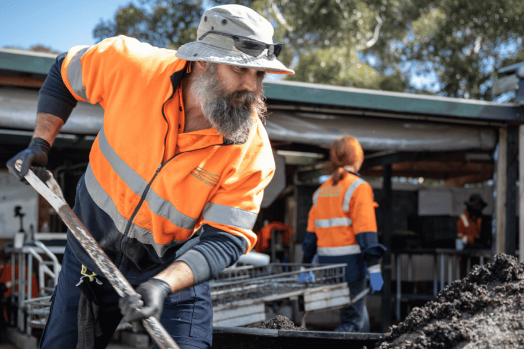 A man shoveling a pile of of quality ecoDynamics soil, is one way to prepare the soil for it's best use.