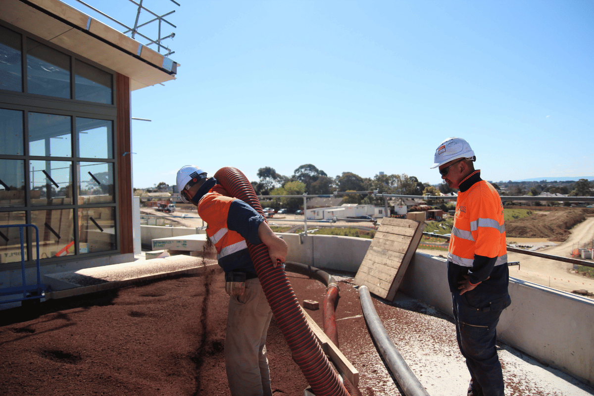 Tow ecoDynamics workers blowing soil with a blower hose from a truck