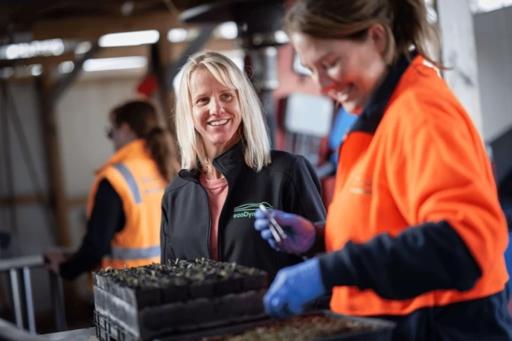 Two female ecoDynamics nursery workers are planting seeds to add to our impact on the environment