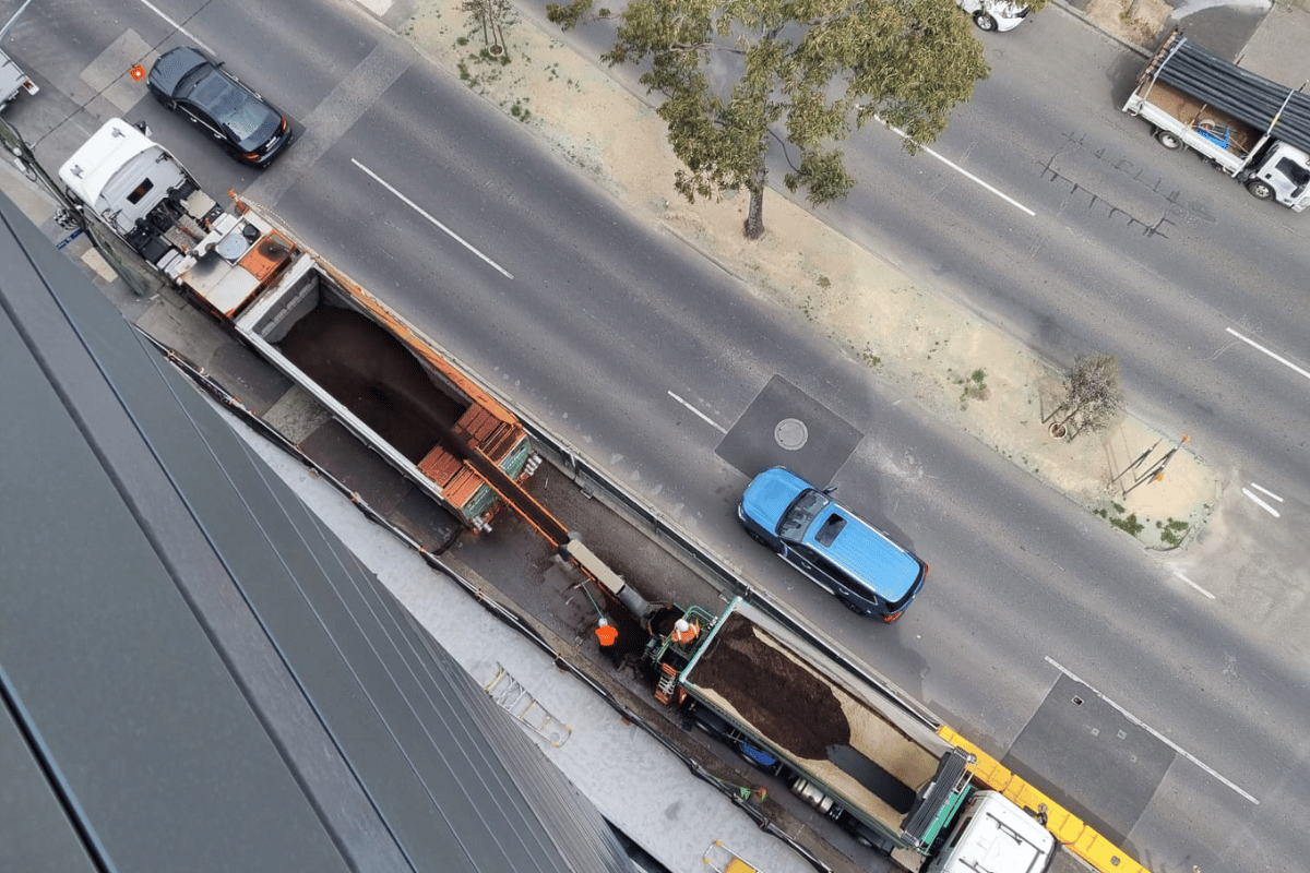 A slinger truck moving materials into a blower truck to get ready for material blowing