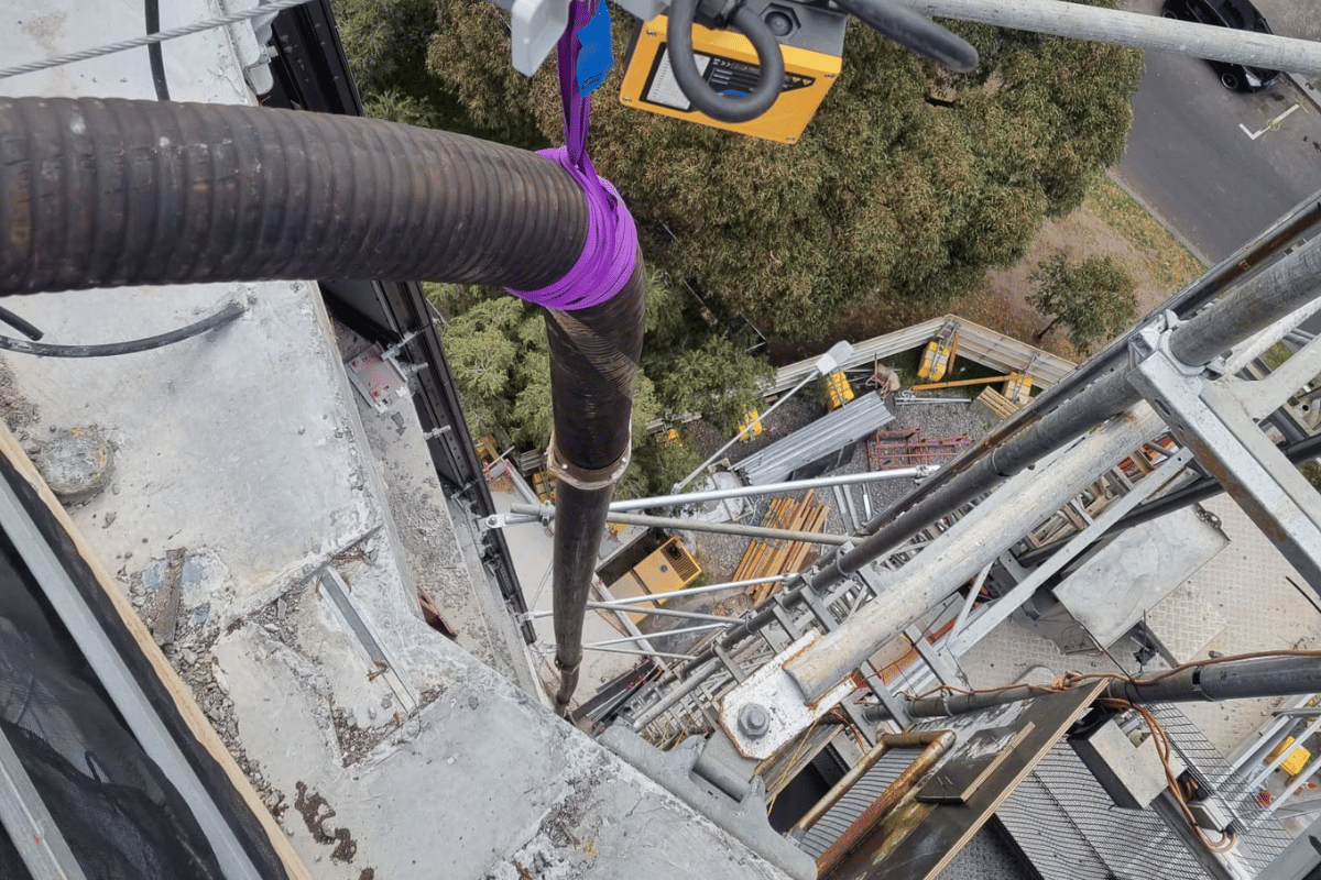 Blower hose stretching over the side of a high-rise building so we can blow soil and aggregates
